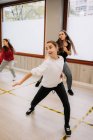 Groupe de jeunes femmes et filles répétant des mouvements de danse hip hop tout en pratiquant dans une salle spacieuse ensemble pendant un cours actif avec instructeur — Photo de stock