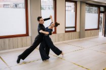 Geschicktes Tanzpaar in eleganter Kleidung, das während des Kurses im Studio Bewegungen des Standardtanzes einübt — Stockfoto