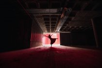 Анонімна танцівниця в одязі танцює з піднятими руками і ногами на театральній сцені під час репетиції — стокове фото