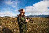 Young female tourist with pouting lips controlling UAV with remote controller while looking away on lawn in Europe — Stock Photo