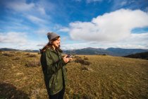 Giovane turista donna con labbra indolenzite che controlla l'UAV con telecomando mentre guarda lontano sul prato in Europa — Foto stock
