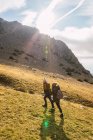 Meilleures amies méconnaissables en vêtements de dessus se promenant sur le mont avec de l'herbe pendant le voyage en Espagne — Photo de stock