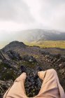 Crop turista anónimo en ropa casual acostado en tierra agitada contra las montañas durante el viaje en España - foto de stock