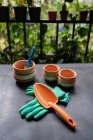 De arriba de la colección de herramientas de jardinería y macetas de cerámica para trasplantar plantas colocadas en la mesa en invernadero - foto de stock