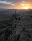 Vue arrière de la femelle méconnaissable debout sur le sommet d'une montagne rocheuse et faisant Tree with Arms Up pose pendant le coucher du soleil — Photo de stock