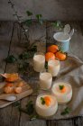 Alto ángulo de sabrosa mousse de mandarina adornado con hojas de menta fresca servida en copas de vidrio sobre mesa de madera - foto de stock