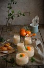 Alto ângulo de mousse de tangerina saborosa decorada com folhas de hortelã frescas servidas em copos de vidro na mesa de madeira — Fotografia de Stock