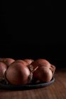 Bando de cebolas frescas não descascadas colocadas na placa na mesa de madeira — Fotografia de Stock