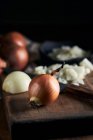 Bol rustique avec des morceaux d'oignon coupé placés près du couteau sur la table à bois dans la cuisine — Photo de stock