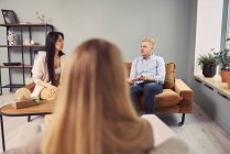 Багатоетнічна пара сидить на дивані і говорить про психічні проблеми під час сеансу терапії з психологом — стокове фото