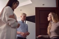 Низкий угол женщины-психолога, стоящей в дверях офиса во время приема у пары, имеющей проблемы в отношениях — стоковое фото