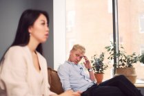 Mulher asiática infeliz levando ao homem indiferente durante sessão de terapia no escritório do psicólogo — Fotografia de Stock