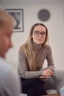Conselheira feminina sentada em poltrona e dando conselhos a cliente irreconhecível durante a consulta de psicoterapia — Fotografia de Stock