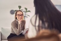 Conselheira feminina alegre ouvindo cliente anônimo enquanto ajuda durante sessão de terapia mental — Fotografia de Stock