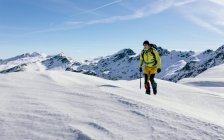 Männlicher Bergsteiger in Unterwäsche, der bei sonnigem Wetter am Hang des schneebedeckten Bergmassivs spazieren geht — Stockfoto