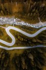Vista aérea de la serpenteante calzada con curvas que corre por la ladera de la montaña con bosques de coníferas en Dolomitas en Italia - foto de stock