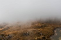 De cima paisagem cênica de lago pequeno cercado por colinas cobertas com nevoeiro e nuvens em Dolomites gama montesa na Itália — Fotografia de Stock