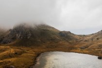 From above scenic landscape of small lake surrounded by hills covered with fog and clouds in Dolomites mountain range in Italy — Stock Photo