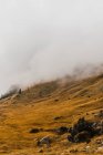 Pintoresco paisaje con áspero pico rocoso empinado y colinas cubiertas de hierba amarilla bajo las nubes en la cordillera de los Dolomitas en Italia - foto de stock