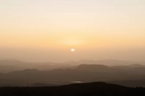 Sunset over mountain range on background of cloudless sky in the evening — Stock Photo