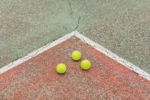 Von oben gelbe Bälle, die beim Training auf dem rissigen Boden des Tennisplatzes platziert wurden — Stockfoto