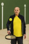 Старший спортсмен підстрибує м'яч на ракетці, готуючись до тенісного матчу на корті — стокове фото