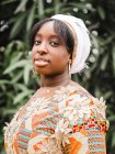 Side view of young African female in kerchief looking at camera against plant in summer — Stock Photo