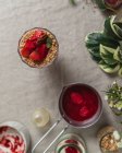 Composición vista superior del vaso de deliciosa bebida de bayas frescas adornada con fresas cortadas y nueces servidas en la mesa - foto de stock