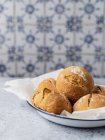 Appetizing pão recém-assado pães amontoados em papel manteiga na placa e servido na mesa da cozinha — Fotografia de Stock