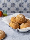 Аппетитные свежеиспеченные булочки с хлебом, набитые на тарелку и подаваемые на кухонном столе — стоковое фото