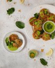 Вкусные аппетитные травяные оладьи, украшенные зеленым соусом петрушки и ломтиками лимона на белом столе — стоковое фото