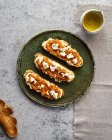 Draufsicht appetitliche frische Toastbrot mit Marmelade und Ziegenkäse auf Teller in der Nähe Krug mit Bio-Olivenöl serviert — Stockfoto