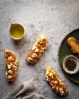 Arranjo aéreo de torradas saudáveis de pão de abóbora com doce geleia e queijo de cabra colocadas na mesa de mármore perto do jarro de azeite — Fotografia de Stock