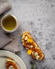 Toasts frais appétissants avec confiture et fromage de chèvre servis sur des assiettes et une table en marbre — Photo de stock