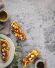 Vista superior apetitosas tostadas frescas con mermelada y queso de cabra servido en platos y mesa de mármol - foto de stock