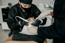 Сверху стоматологи с зубной дрелью и шприцем с воздушной водой делают лечение зубов для клиента в современной клинике — стоковое фото