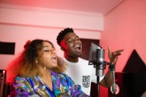 Jovens vocalistas afro-americanos com penteado afro e olhos fechados cantando em microfone profissional — Fotografia de Stock