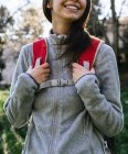 Anonyme heureux optimiste jeune randonneuse en vêtements de sport avec sac à dos profiter du voyage dans la forêt verte par une journée ensoleillée — Photo de stock