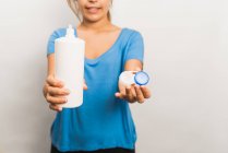 Crop mujer anónima con camisa azul casual que muestra un paquete reutilizable de plástico con lentes de contacto contemporáneas y botella con solución - foto de stock