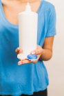Ritaglia anonima donna indossando camicia blu casual mostrando confezione riutilizzabile in plastica con lenti a contatto contemporanee e bottiglia con soluzione — Foto stock