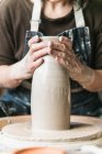 Ritagliato irriconoscibile femminile artigianale creazione di stoviglie in argilla sulla ruota ceramica mentre si lavora in studio d'arte — Foto stock