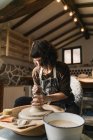 Konzentrierte Kunsthandwerkerin kreiert Tongeschirr auf Töpferscheibe bei der Arbeit im Kunstatelier — Stockfoto