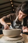 Орієнтована жіноча майстриня з використанням керамічного колеса та створення глиняного посуду ручної роботи в майстерні — стокове фото