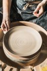 Зверху врожаю невідомий майстер створює глиняний посуд на керамічному колесі в студії — стокове фото