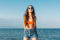 Adolescente hipster de longue date confiante en tenue d'été élégante et lunettes de soleil profitant des vacances d'été au bord de la mer — Photo de stock