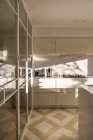 Interieur einer modernen Wohnküche mit hellen Möbeln und Spiegelelementen im Tageslicht — Stockfoto