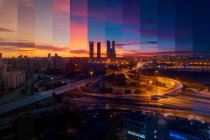 Gratte-ciel contemporain et maisons à étages extérieurs contre la chaussée et les poteaux lumineux brillants à Madrid au coucher du soleil — Photo de stock