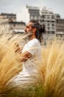 Небритый латиноамериканец в белой одежде сидит с закрытыми глазами во время медитации среди золотой травы при дневном свете — стоковое фото