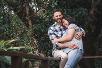 Fröhliches verliebtes Paar umarmt sich auf Holzterrasse des Hauses im Wald und lacht — Stockfoto