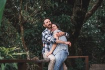Couple joyeux amoureux embrassant sur la terrasse en bois de la maison dans les bois et riant — Photo de stock